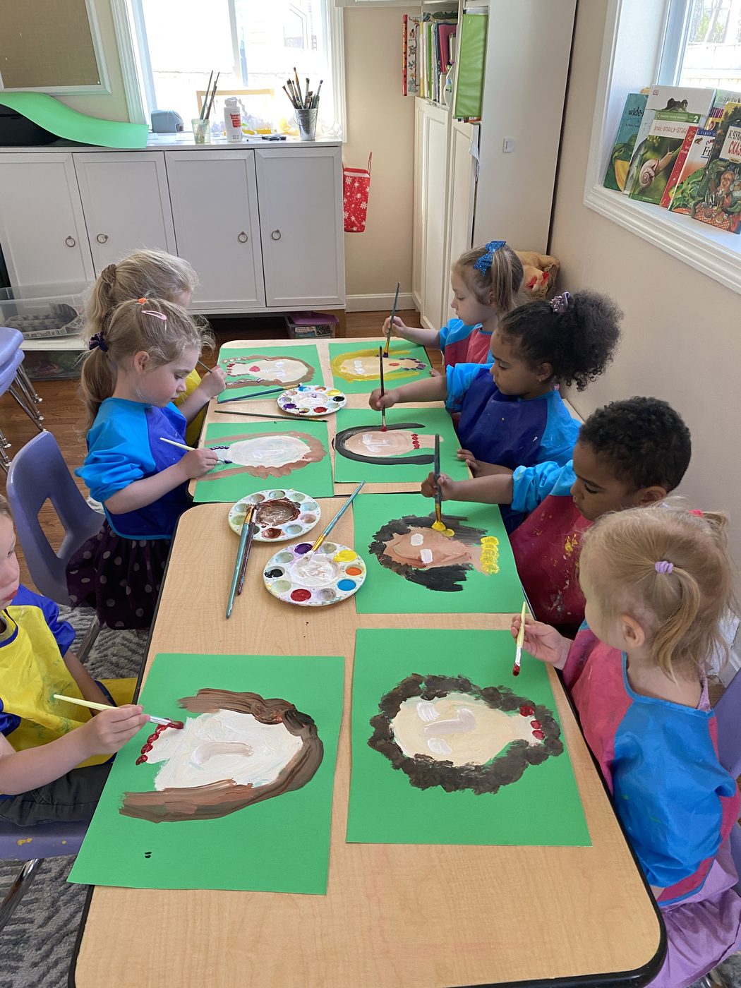 Children painting portraits at the art table