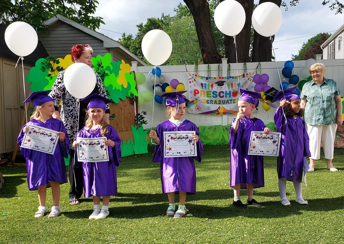 Children in graduation caps and gowns holding certificates at a preschool graduation ceremony